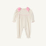 The Long Sleeve Ryleigh Romper by The Beaufort Bonnet Company is crafted from Palmetto Pearl & Richmond Red Microdot corduroy. This cozy winter outfit for little ones features a cream base adorned with small polka dots, long sleeves, pink trim, and two large Richmond Red bows on the shoulders. Ruffled edges on the cuffs and ankles add an extra touch of charm.