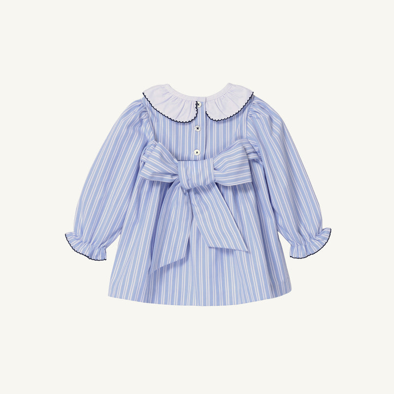 The Beaufort Bonnet Company Long Sleeve Dollie Mae Dress - Park City Periwinkle Ticking Stripe & Worth Avenue White features a white scalloped collar, back button closure, and a large fabric bow at the waist.