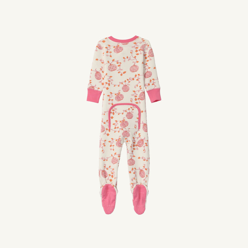 The Beaufort Bonnet Company’s Noelle’s Night Night - Gourd-geous (Palmetto Pearl) with Palm Beach Pink is a cozy waffle knit one-piece girls’ pajama laid flat on a white background. These white footed pajamas feature pink cuffs, matching pink soles, an all-over pink pomegranate-inspired print, and a pink-trimmed flap on the back.