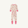 The Beaufort Bonnet Company’s Noelle’s Night Night - Gourd-geous (Palmetto Pearl) with Palm Beach Pink is a cozy waffle knit one-piece girls’ pajama laid flat on a white background. These white footed pajamas feature pink cuffs, matching pink soles, an all-over pink pomegranate-inspired print, and a pink-trimmed flap on the back.