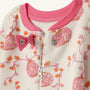 Close-up of The Beaufort Bonnet Company’s Noelle’s Night Night - Gourd-geous (Palmetto Pearl) with Palm Beach Pink, a textured white baby onesie featuring pink floral patterns, pink trim around the collar, and a pink bow near the snap buttons and zipper closure—perfect cozy sleepwear for your little one.
