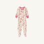 Noelle’s Night Night - Gourd-geous (Palmetto Pearl) with Palm Beach Pink from The Beaufort Bonnet Company is a cozy baby sleeper featuring long sleeves, footed legs, pink cuffs, and a charming floral print adorned with pink and red flowers and fruits. A small pink bow decorates the neckline. The sleepwear is displayed on a white background.