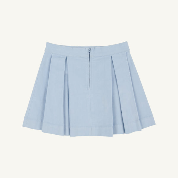The Parson Pleated Skirt in Buckhead Blue Corduroy by The Beaufort Bonnet Company is a light blue corduroy mini skirt featuring pleats, a front zipper, and a waistband, displayed against a plain white background.