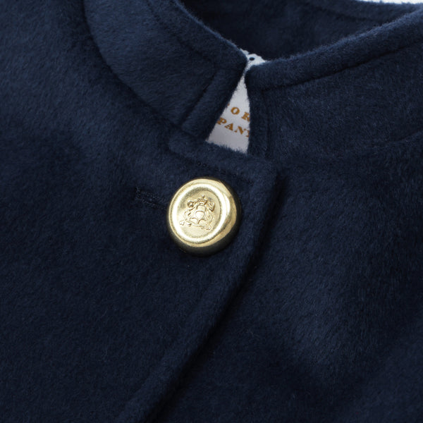 Detailed view of The Beaufort Bonnet Company’s Penelope Peacoat - Nantucket Navy for girls, highlighting the gold button adorned with a lion emblem near the collar and a glimpse of a white clothing tag beneath.