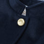 Detailed view of The Beaufort Bonnet Company’s Penelope Peacoat - Nantucket Navy for girls, highlighting the gold button adorned with a lion emblem near the collar and a glimpse of a white clothing tag beneath.