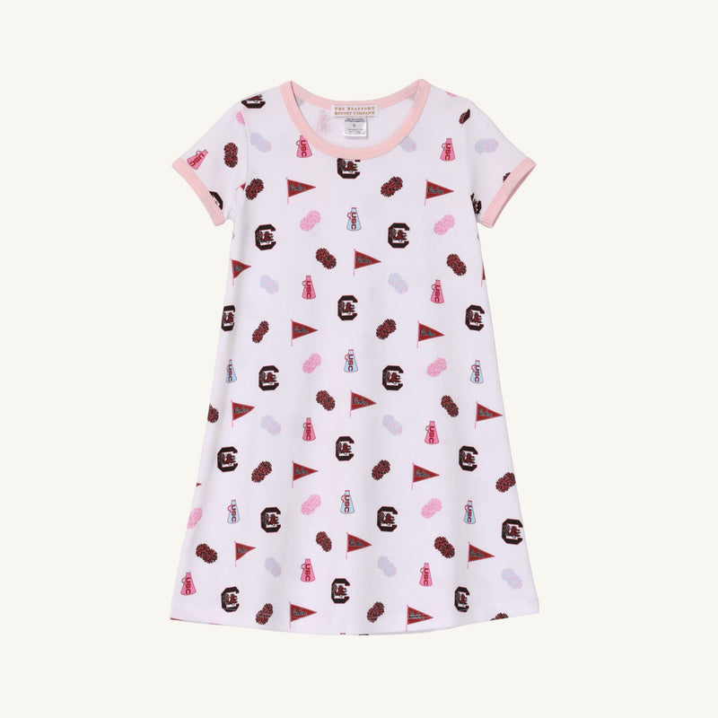 Introducing the USC Polly Play Dress – South Carolina Spirit with Palm Beach Pink by The Beaufort Bonnet Company. This short-sleeved dress is crafted from soft Pima Cotton and showcases a pink-collared design adorned with South Carolina Gamecocks logos, pennants, and mascots in maroon, pink, purple, and blue against a crisp white background for true South Carolina spirit.