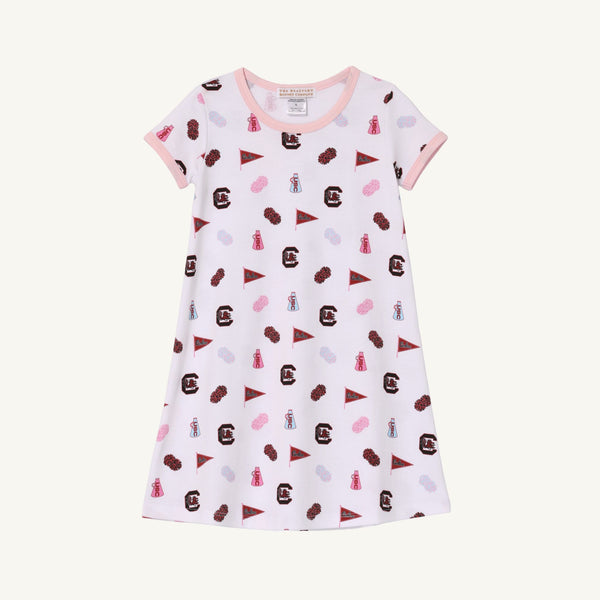 Introducing the USC Polly Play Dress – South Carolina Spirit with Palm Beach Pink by The Beaufort Bonnet Company. This short-sleeved dress is crafted from soft Pima Cotton and showcases a pink-collared design adorned with South Carolina Gamecocks logos, pennants, and mascots in maroon, pink, purple, and blue against a crisp white background for true South Carolina spirit.