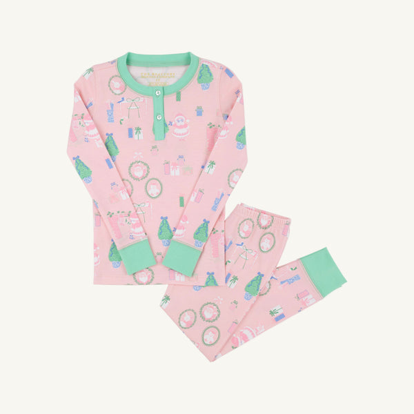 Sara Jane’s Sweet Dream Set - Mrs. Claus Collage with Grace Bay Green by The Beaufort Bonnet Company is a pink long-sleeve Christmas pajama set with green cuffs and collar, adorned with festive prints such as wreaths, presents, and Santa Claus, laid flat on a white background.
