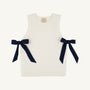 The Beaufort Bonnet Company’s Shae Sweater Vest in Palmetto Pearl with Nantucket Navy features ribbed edges and two large navy blue bows on each side, crafted from 100% cotton. Laid flat against a plain, light background, this sleeveless vest is the perfect addition to any girl’s autumn wardrobe.