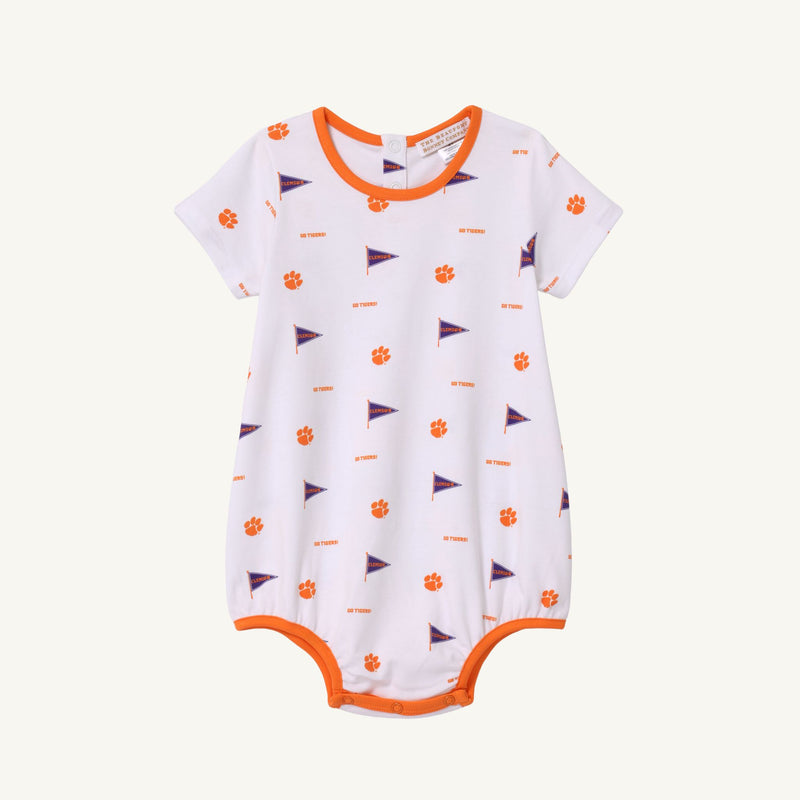 The Beaufort Bonnet Company Clemson Short Sleeve Patton Play Bubble - Tiger Triumph with Clemson Orange is a white baby romper with orange trim, short sleeves, and convenient bottom snaps. It features an all-over print of small orange Tiger paws and purple pennants with “CLEMSON” text, perfect for celebrating Tiger Triumph spirit.