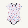 Ole Miss Short Sleeve Patton Play Bubble - Gawsh Almighty with Nantucket Navy by The Beaufort Bonnet Company, crafted from soft Pima Cotton and adorned with small blue flags and circular red, white, and blue emblems. Finished with dark blue trim along the neck, sleeves, and leg openings—perfect for little Ole Miss fans.