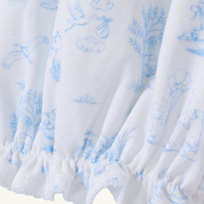 Sir Proper’s Sweet Arrival (Beale Street Blue) Bundle by The Beaufort Bonnet Company features white fabric adorned with light blue illustrations—including a stork carrying a bundle, trees, clouds, houses, and animals. This charming layette gown is gathered with elastic at the bottom edge and comes as part of an adorable everyday set with Bradley Bear, making it a thoughtful baby shower gift.