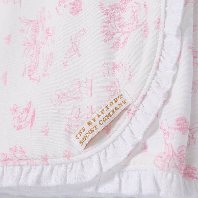 Crafted from soft pima cotton, the Sir Proper’s Sweet Arrival (Hamptons Hot Pink) Accessories Bundle by The Beaufort Bonnet Company features a white fabric adorned with pink, vintage-inspired illustrations and delicate ruffled edges. A beige and gold label reading THE BEAUFORT BONNET COMPANY is sewn onto each piece. This charming set—including a Baby Buggy Blanket, Oopsie Daisy Burp Cloth, and Burp Me Bib—makes a thoughtful baby shower gift.