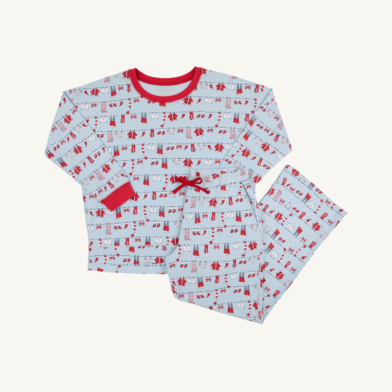 The Snooze Button Set - Santa’s Laundry Line by The Beaufort Bonnet Company is a festive children’s pajama set featuring a white background with red trim and a whimsical print of red and blue winter clothing hanging on clotheslines. This Christmas set includes a cozy long-sleeve top and matching pants, perfect for comfortable holiday lounging.