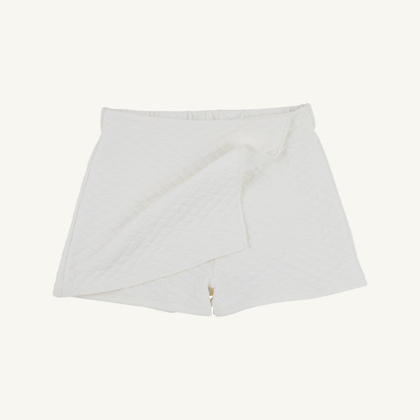 Stella Skort - Quilted Palmetto Pearl by The Beaufort Bonnet Company: This white quilted skort showcases a wrap-front design with a subtle diamond pattern and a fitted waistband, bringing together comfort and modern elegance in a chic girls’ skirt shorts style. Displayed against a plain white background.
