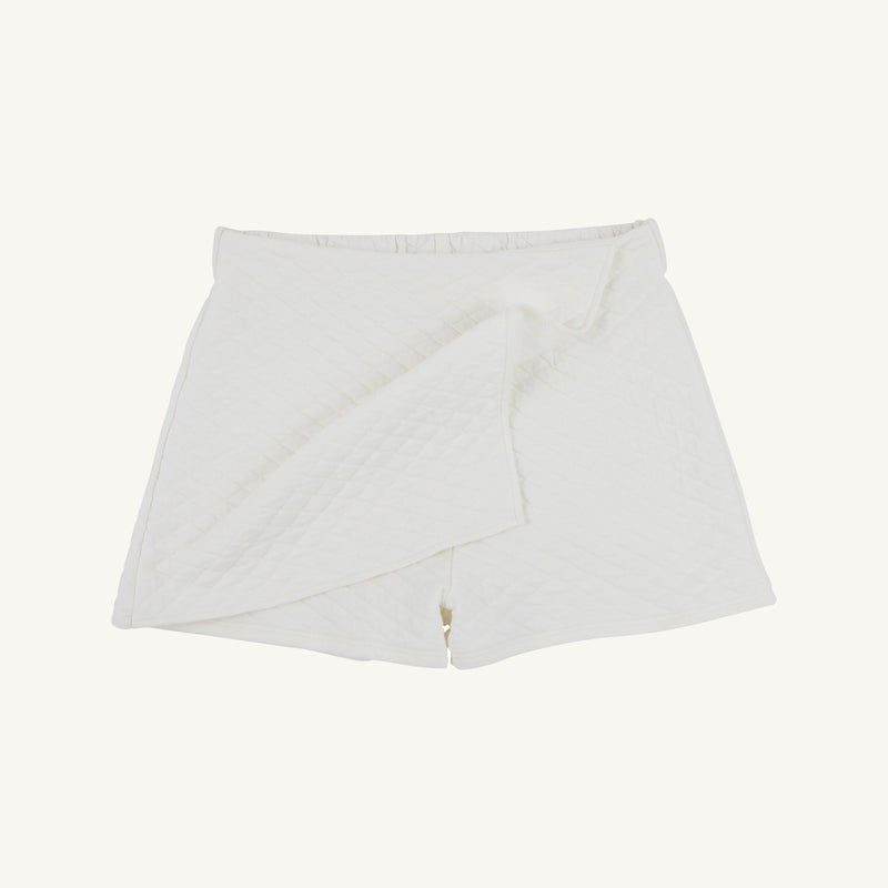 Stella Skort - Quilted Palmetto Pearl by The Beaufort Bonnet Company: This white quilted skort showcases a wrap-front design with a subtle diamond pattern and a fitted waistband, bringing together comfort and modern elegance in a chic girls’ skirt shorts style. Displayed against a plain white background.