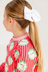 A child wearing a pink and white striped Cassidy Comfy Crewneck - Distinguished Doggies with Hamptons Hot Pink featuring dog illustrations in decorative frames.