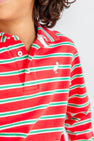 A child wearing The Beaufort Bonnet Company’s Long Sleeve Prim & Proper Polo & Onesie in Richmond Red, Kiawah Kelly Green, and Palmetto Pearl Stripe, featuring a collared neckline with buttons and a small white bird logo on the chest. Only the lower half of the child’s face and torso are visible in the image.