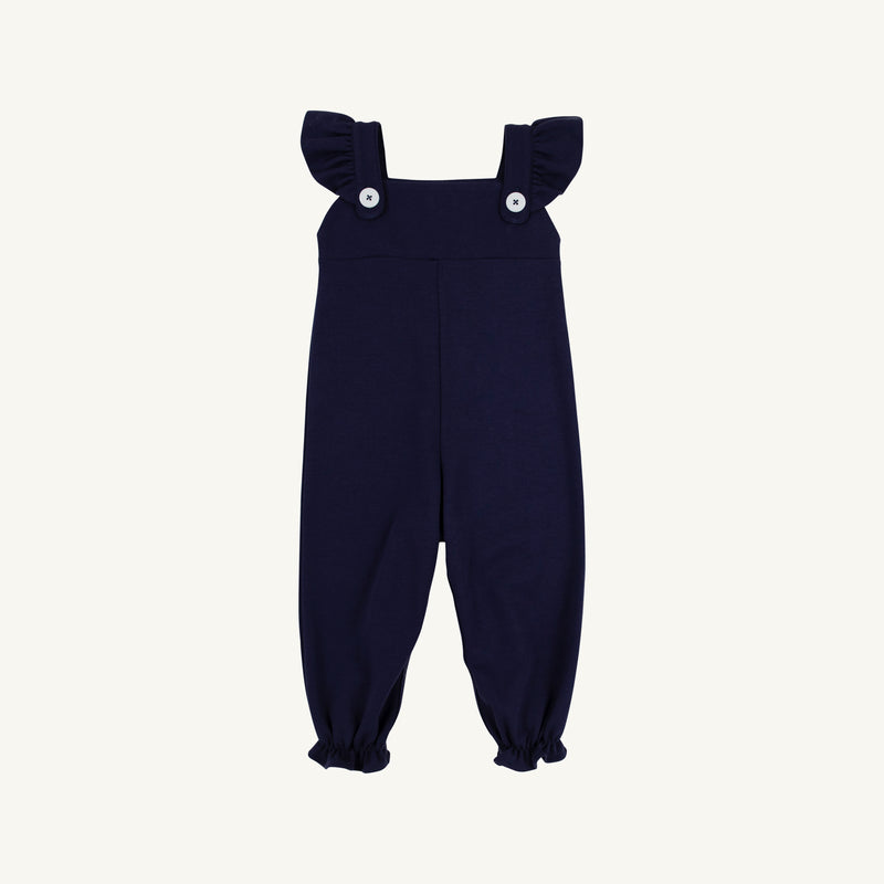 Violet’s Vintage Overalls in Nantucket Navy with Worth Avenue White by The Beaufort Bonnet Company feature ruffled shoulder straps, two white buttons on the front, and elasticized ankle cuffs. Crafted from soft Pima Cotton Knit, they are displayed against a plain white background.