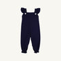 Violet’s Vintage Overalls in Nantucket Navy with Worth Avenue White by The Beaufort Bonnet Company feature ruffled shoulder straps, two white buttons on the front, and elasticized ankle cuffs. Crafted from soft Pima Cotton Knit, they are displayed against a plain white background.