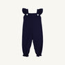 Violet’s Vintage Overalls in Nantucket Navy with Worth Avenue White by The Beaufort Bonnet Company feature ruffled shoulder straps, two white buttons on the front, and elasticized ankle cuffs. Crafted from soft Pima Cotton Knit, they are displayed against a plain white background.