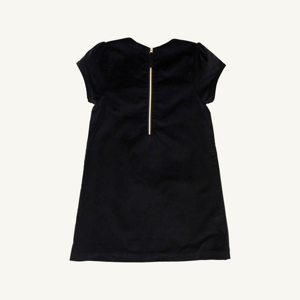 A short-sleeve Betts Bow Dress - Newport Night Velveteen by The Beaufort Bonnet Company, shown from the back with a visible gold zipper down the upper center. Velvet bows lend a festive charm, making it a delightful holiday dress when laid flat against a plain, light background.