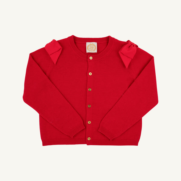 The Beaufort Bonnet Company’s Cambridge Cardigan – Richmond Red with Bows features long sleeves, gold buttons, and two fabric bows on the shoulders. Laid flat on a plain white background, this charming piece is perfect for adding a sweet touch to your little one’s wardrobe.