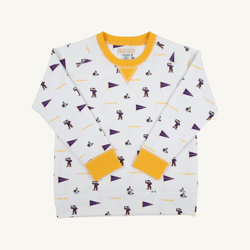 The Beaufort Bonnet Company’s LSU Cassidy Comfy Crewneck - Tenacious Tigers with LSU Gold is a white long-sleeve sweatshirt with yellow cuffs and collar, covered in a playful pattern of purple pennants, tigers, and the word “TIGERS.” Inspired by Tenacious Tigers spirit, this LSU crewneck is displayed laid flat on a white background.