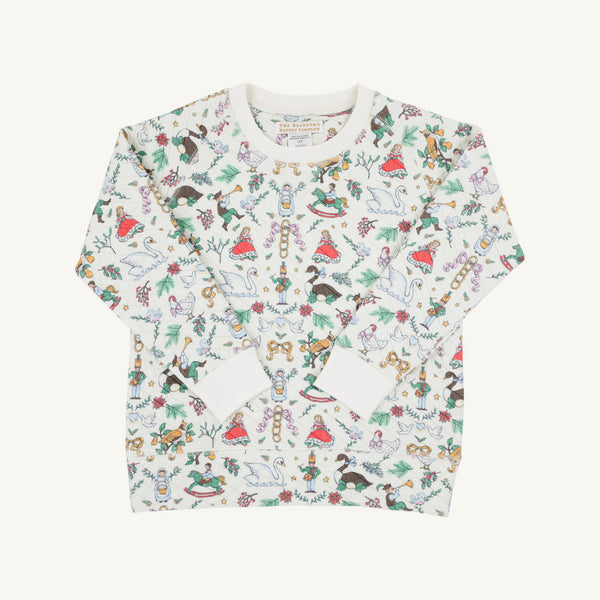 Cassidy Comfy Crewneck - 12 Days of Christmas by The Beaufort Bonnet Company is a long-sleeve children’s shirt featuring colorful holiday-themed illustrations—nutcrackers, reindeer, rocking horses, and trees—on a white background, making it the perfect festive top for holiday parties inspired by the classic “12 Days of Christmas.”.