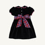 Introducing the Cindy Lou Sash Dress - Newport Night Velveteen with Bucktown Tartan by The Beaufort Bonnet Company. Perfect for holiday occasions, this charming children’s dress features short sleeves, white buttons, and a plaid Bucktown Tartan collar trim. A large red and blue plaid sash bow at the waist adds a festive touch, while its soft cotton velveteen construction ensures comfort. Displayed on a plain background.