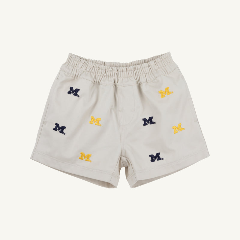 Introducing the Michigan Critter Sheffield Shorts in Saratoga Stone by The Beaufort Bonnet Company. These light beige shorts feature an elastic waistband and are adorned with embroidered blue and yellow Michigan logos throughout, combining comfort with spirited University of Michigan style.