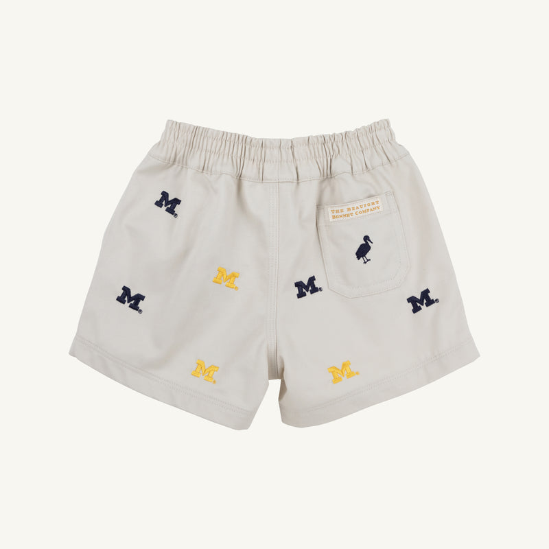 The Beaufort Bonnet Company’s Michigan Critter Sheffield Shorts in Saratoga Stone feature an elastic waistband, embroidered blue and yellow Michigan logos, and a small back pocket with a label and bird icon. These shorts combine comfort and school spirit for any fan.