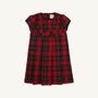 The Darcy Dress - Paces Mill Plaid by The Beaufort Bonnet Company is displayed on a plain white background, showcasing its red and green plaid short sleeves, pleated skirt, and charming bow detailing on the front bodice.