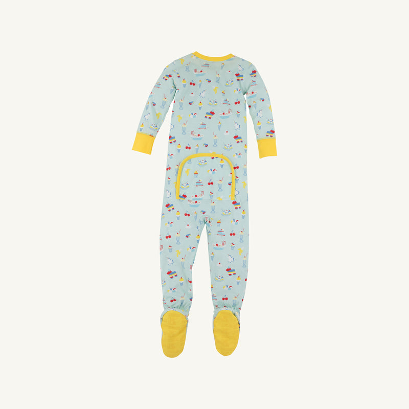 The Beaufort Bonnet Company’s Fallon Footie Pajamas – Ice Cream Daydream (Blueberry Blue) with Nana Banana—feature a soft cotton jersey in a light blue hue, long sleeves, and yellow cuffs and feet. This cozy footed onesie is decorated with colorful playful prints of animals and vehicles, and includes a convenient buttoned flap on the back.