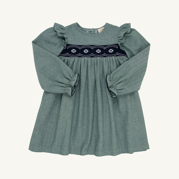 The Long Sleeve Daphne Dress in Grier Green Herringbone by The Beaufort Bonnet Company features ruffled shoulders and navy and white smocked floral embroidery across the chest, shown on a plain white background.