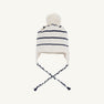 The Beaufort Bonnet Company’s Parrish Pom Pom Hat in Palmetto Pearl with Nantucket Navy Stripe features soft 100% cotton knit, stylish black horizontal stripes, ear flaps with braided ties, and a large pom-pom on top—a cozy finishing touch for your fall outfit. Shown against a plain light background.
