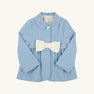 A light blue Pippa Peacoat by The Beaufort Bonnet Company in Barrington Blue with Palmetto Pearl, designed for toddlers and featuring long sleeves, a white Peter Pan collar trim, a single front button, and a large white bow at the waist.