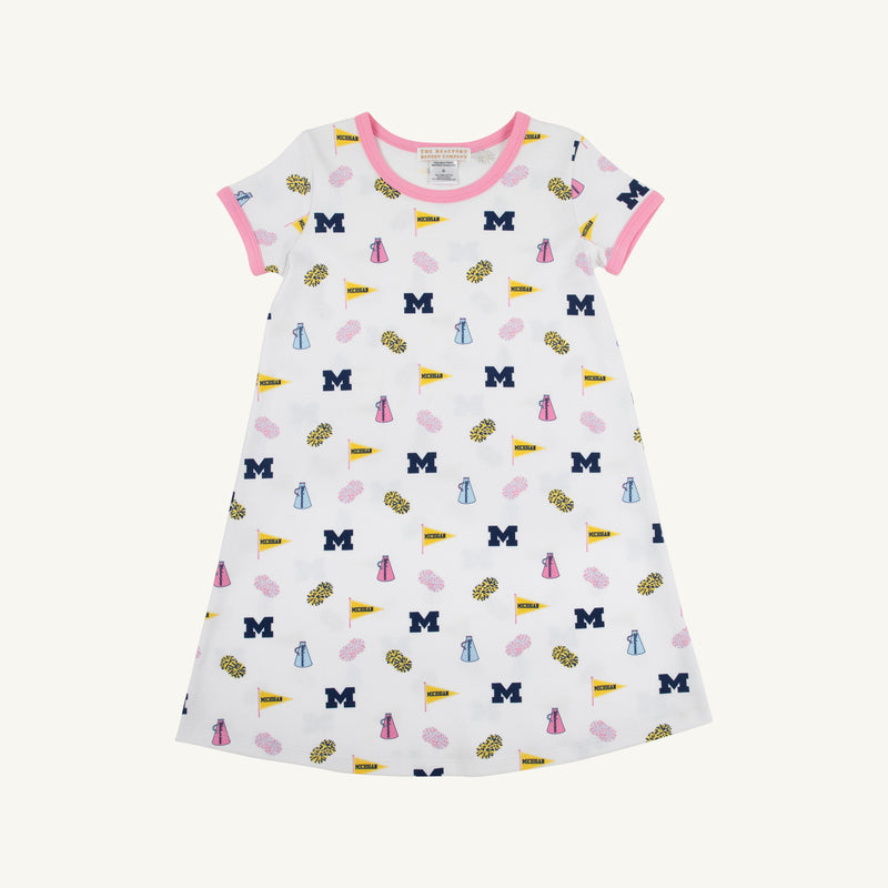 The Beaufort Bonnet Company’s Michigan Polly Play Dress - Bold in Blue with Hamptons Hot Pink features a white short-sleeve design trimmed in pink and decorated with University of Michigan M logos, yellow pennants, pom-poms, and megaphones. Made from 100% Pima Cotton for ultimate comfort, it’s perfect for showing your Bold in Blue spirit!.