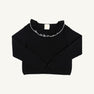 The Beaufort Bonnet Company’s Reece Ruffle Sweater - Newport Night with Palmetto Pearl is a long-sleeve holiday sweater featuring a charming ruffled collar and white decorative stitching along the neckline, displayed flat against a plain white background. Made from 100% cotton for both comfort and style.