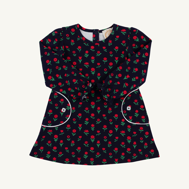 The Beaufort Bonnet Company Sadie Sweatshirt Dress - Prescott Farm Flowers with Worth Avenue White is a navy blue long-sleeved dress featuring a repeating floral pattern, two front pockets with white trim, and white button accents.