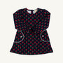 The Beaufort Bonnet Company Sadie Sweatshirt Dress - Prescott Farm Flowers with Worth Avenue White is a navy blue long-sleeved dress featuring a repeating floral pattern, two front pockets with white trim, and white button accents.
