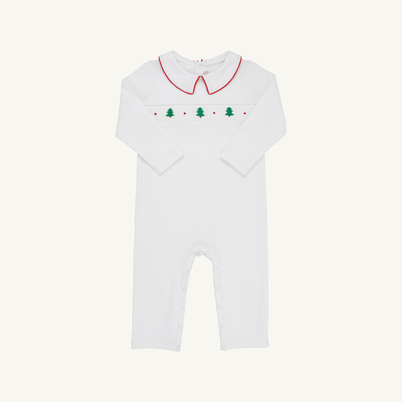 The Samuel Smocked Romper - Worth Avenue White & Richmond Red with Trees is a white long-sleeved Pima cotton romper with a red-trimmed collar and a smocked chest panel featuring green Christmas trees and red dots.