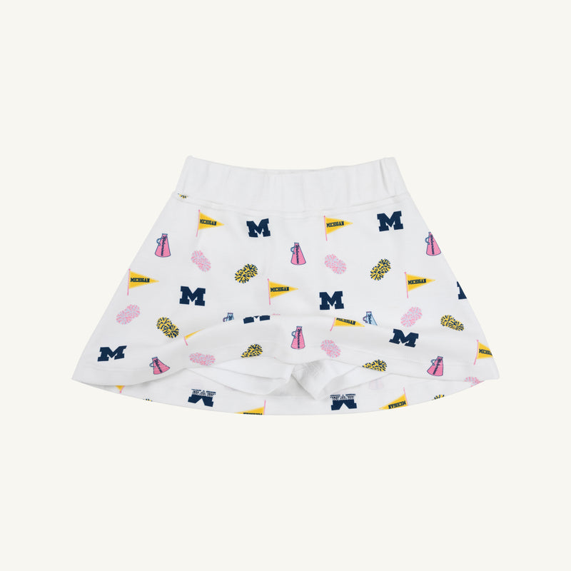 The Michigan Searcy Skort by The Beaufort Bonnet Company features Worth Avenue White Pima cotton with a comfortable elastic waistband and a bold, scattered pattern of blue “M” letters, yellow pennants, pink pom-poms, and megaphones—making it the perfect choice for a spirited gameday look.