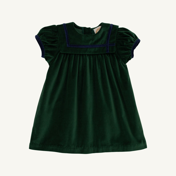 The Beaufort Bonnet Company’s Short Sleeve Patsy’s Party Dress in Grier Green Velveteen with Nantucket Navy features puffed short sleeves, a square yoke, navy blue trim, and gentle pleats for a simple, classic holiday look. The toddler dress is laid flat on a white background.
