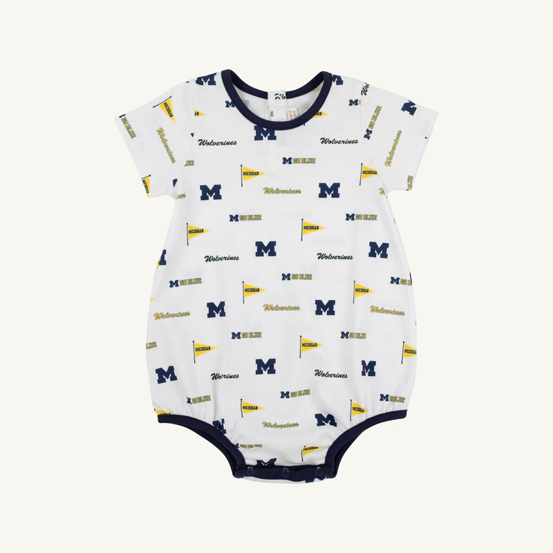Dress your little one for game day in the Michigan Short Sleeve Patton Play Bubble - Bold in Blue with Michigan Blue by The Beaufort Bonnet Company. This adorable white baby romper is made from soft Pima Cotton Knit and features short sleeves, navy trim on the collar, sleeves, and leg openings, and a playful design with repeating University of Michigan logos, blue “M” letters, yellow flags, and “Wolverines” text—making it the perfect outfit for your future fan!.