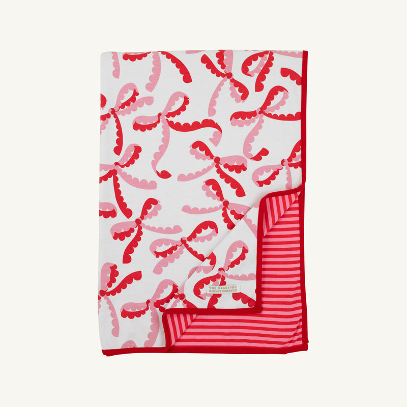 A folded Silent Night Throw - Bonnie Scot Bows with Richmond Red and Hamptons Hot Pink Stripe featuring a red and pink bow pattern on one side and red and pink horizontal stripes on the reverse.