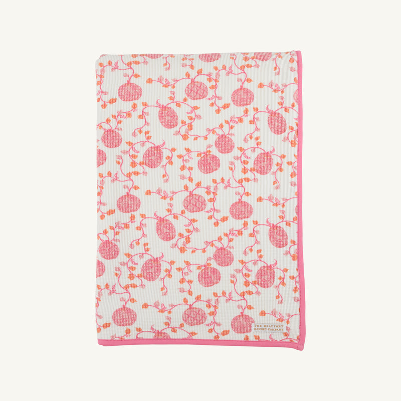 The Silent Night Throw - Gourd-geous (Palmetto Pearl) with Romany Rose by The Beaufort Bonnet Company features a cozy white design with a pink border, adorned with charming pink and orange pomegranates and vines, reminiscent of the comforting warmth of a waffle knit throw.