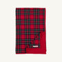 A folded Silent Night Throw - Society Prep Plaid blanket in a red, green, and navy plaid pattern with a solid red backing.