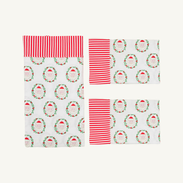Add festive charm to your holiday table setting with the Sleep Tight Sheet Set - North Pole Portrait with Richmond Red Stripe by The Beaufort Bonnet Company, featuring a cheerful Christmas-themed design of red and white stripes paired with Santa Claus faces framed by holly wreaths on a crisp white background.