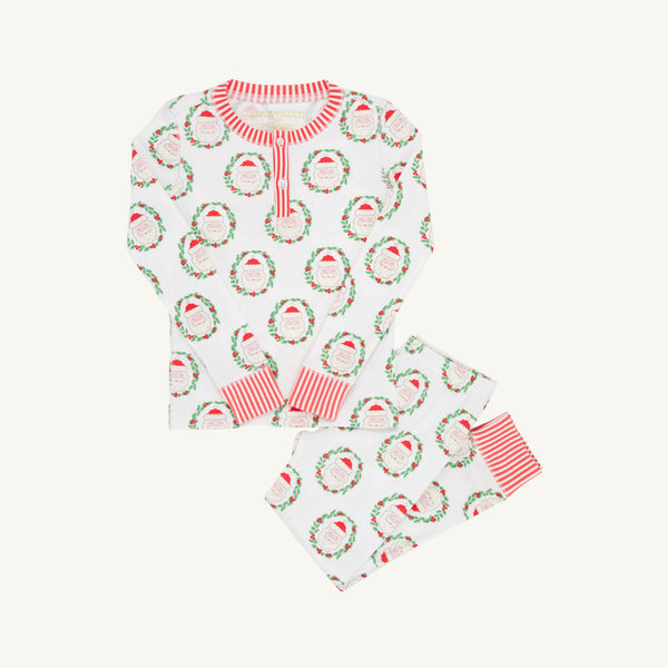 Introducing Sutton’s Sweet Dream Set - North Pole Portrait with Richmond Red Stripe by The Beaufort Bonnet Company: an off-white children’s pajama set featuring a festive Christmas print of Santa faces inside green wreaths. The top includes buttons at the collar and coordinates perfectly with the pants, both finished with rich red-striped cuffs.